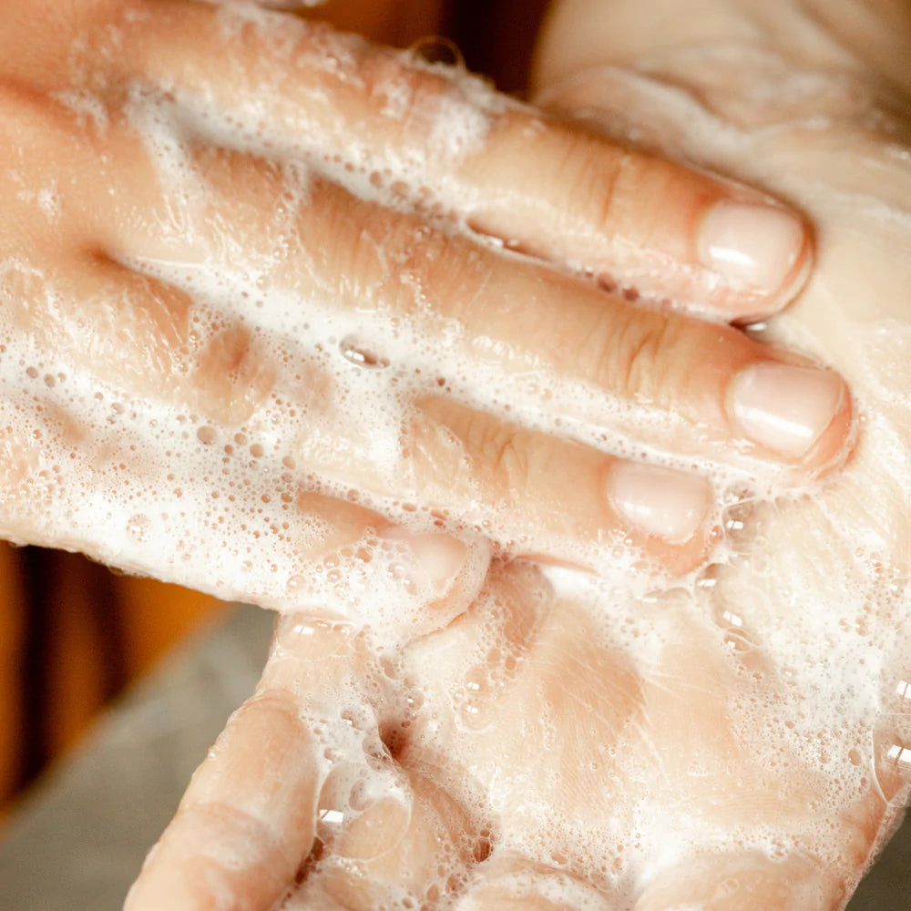 Mains moussantes entrain de frotter le savon liquide le marque Refyld.