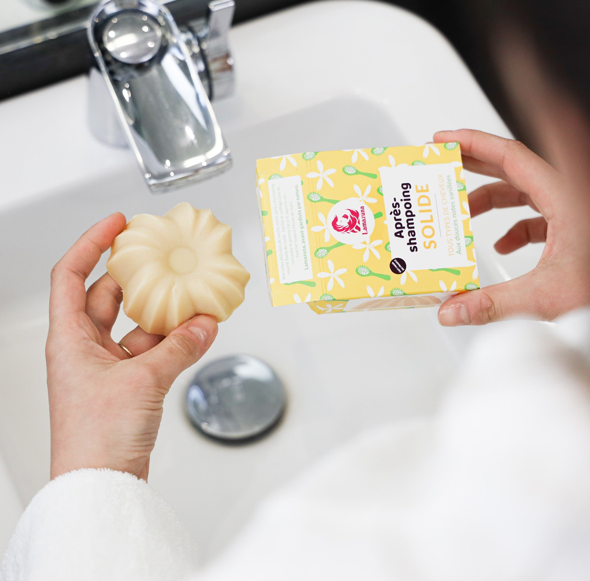 Après-shampoing de la marque Lamazuna, senteur vanille avec son packaging jaune au dessus d'un évier