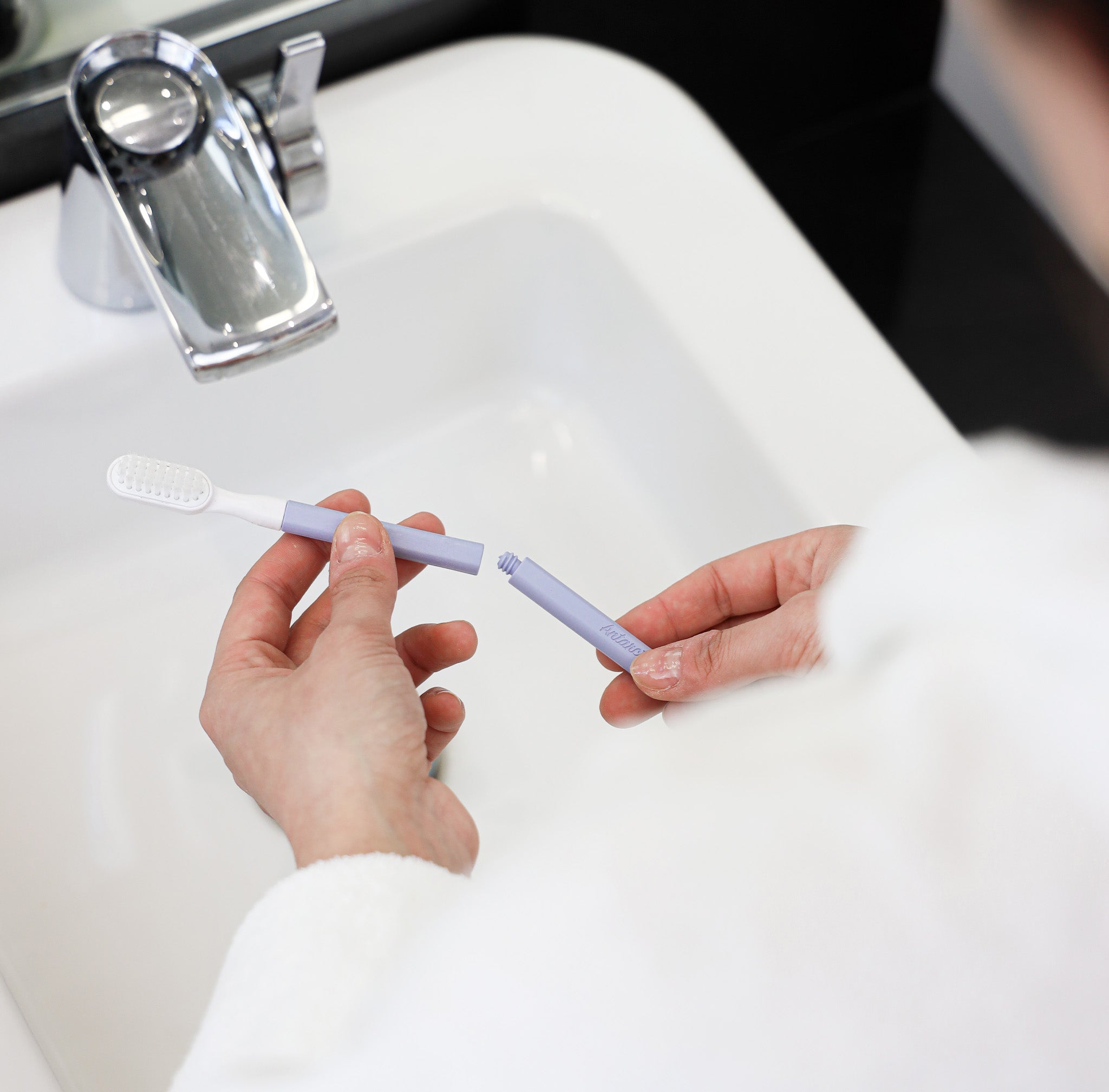 Brosse à dent entrain d'être assemblée au dessus d'un évier avec un manche de couleur lilas