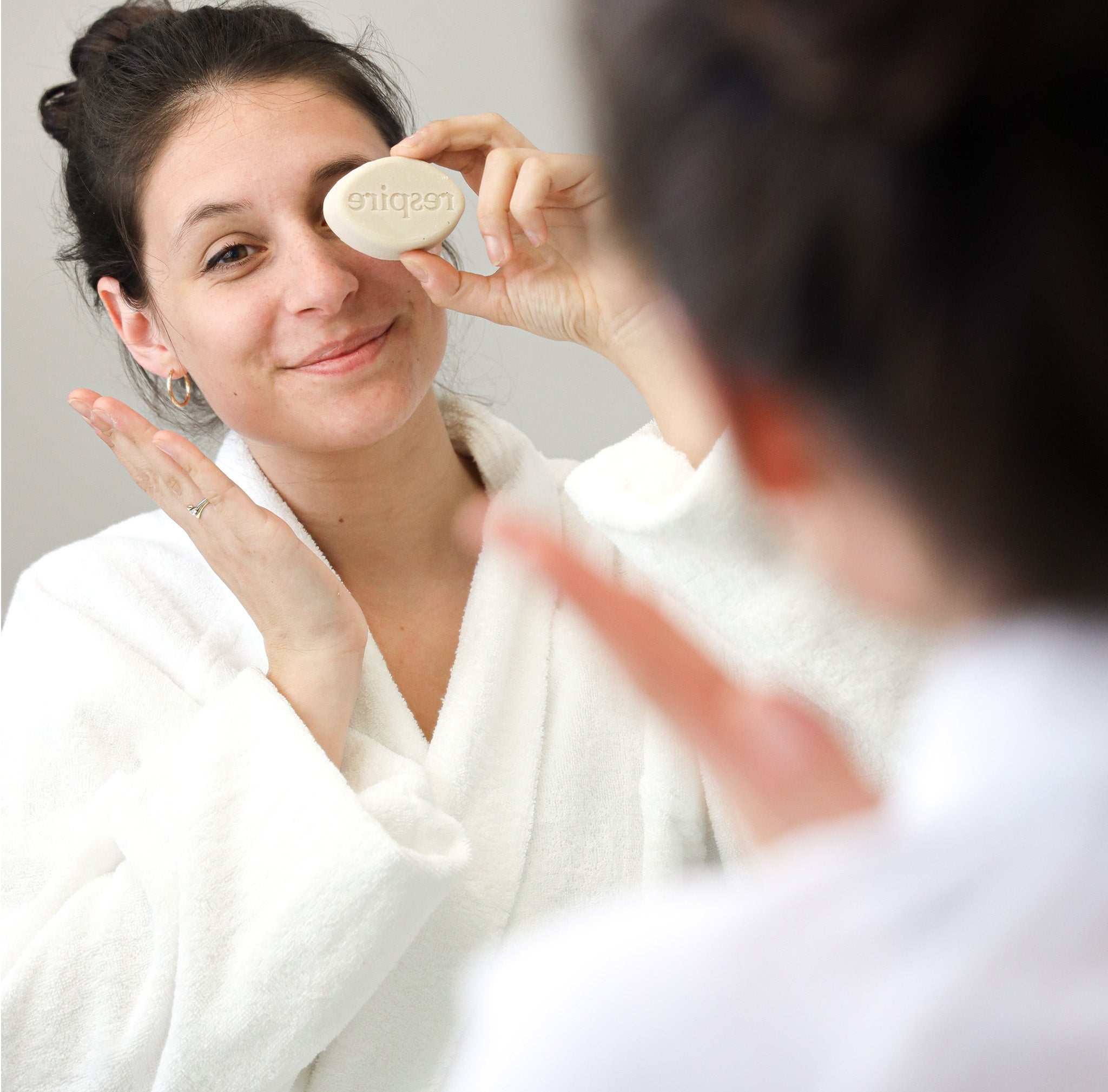 Utilisation du nettoyant visage sur la peau du visage d'une femme en peignoir